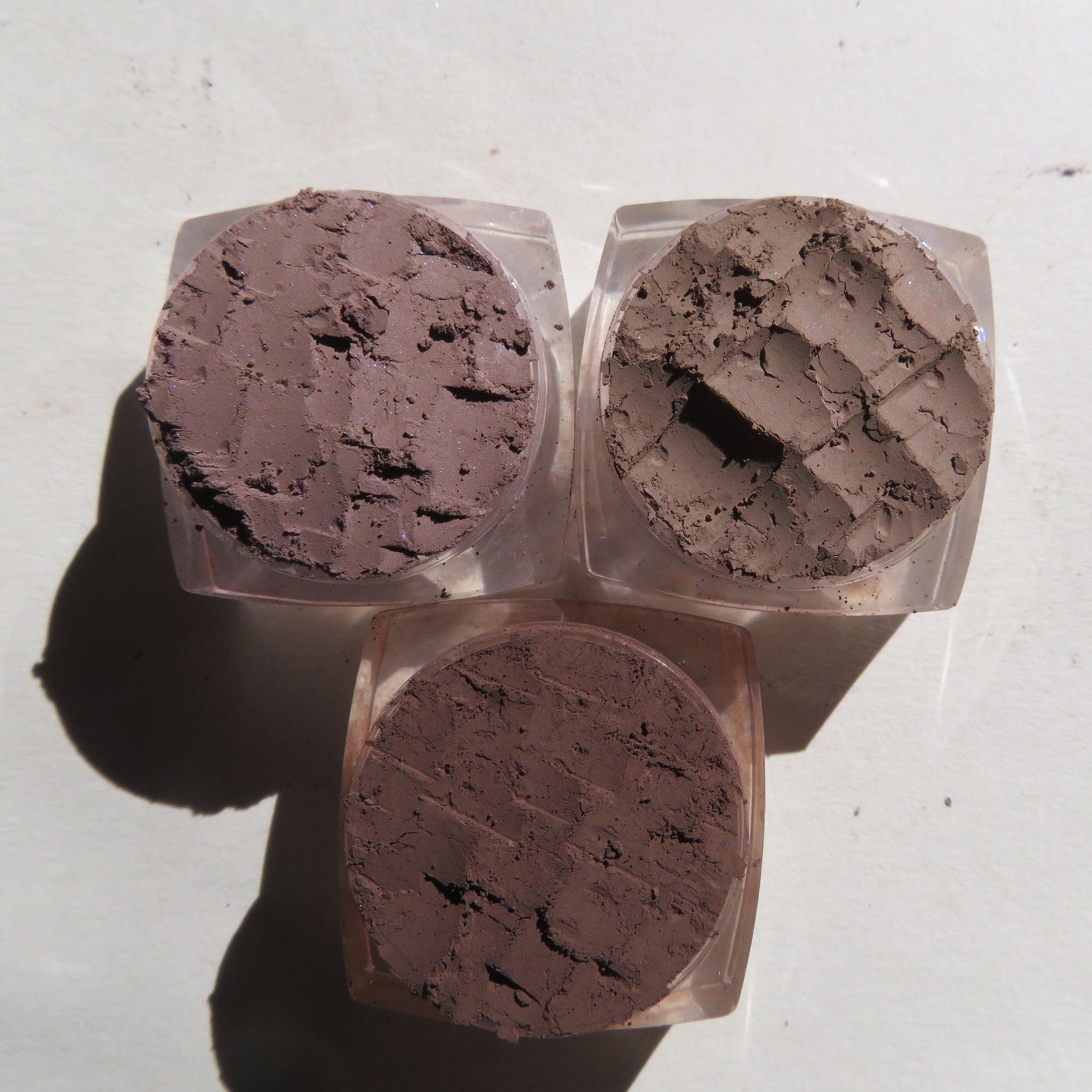 Side view of matte brown mineral eye shadow set with loose powder pigments in compact jar