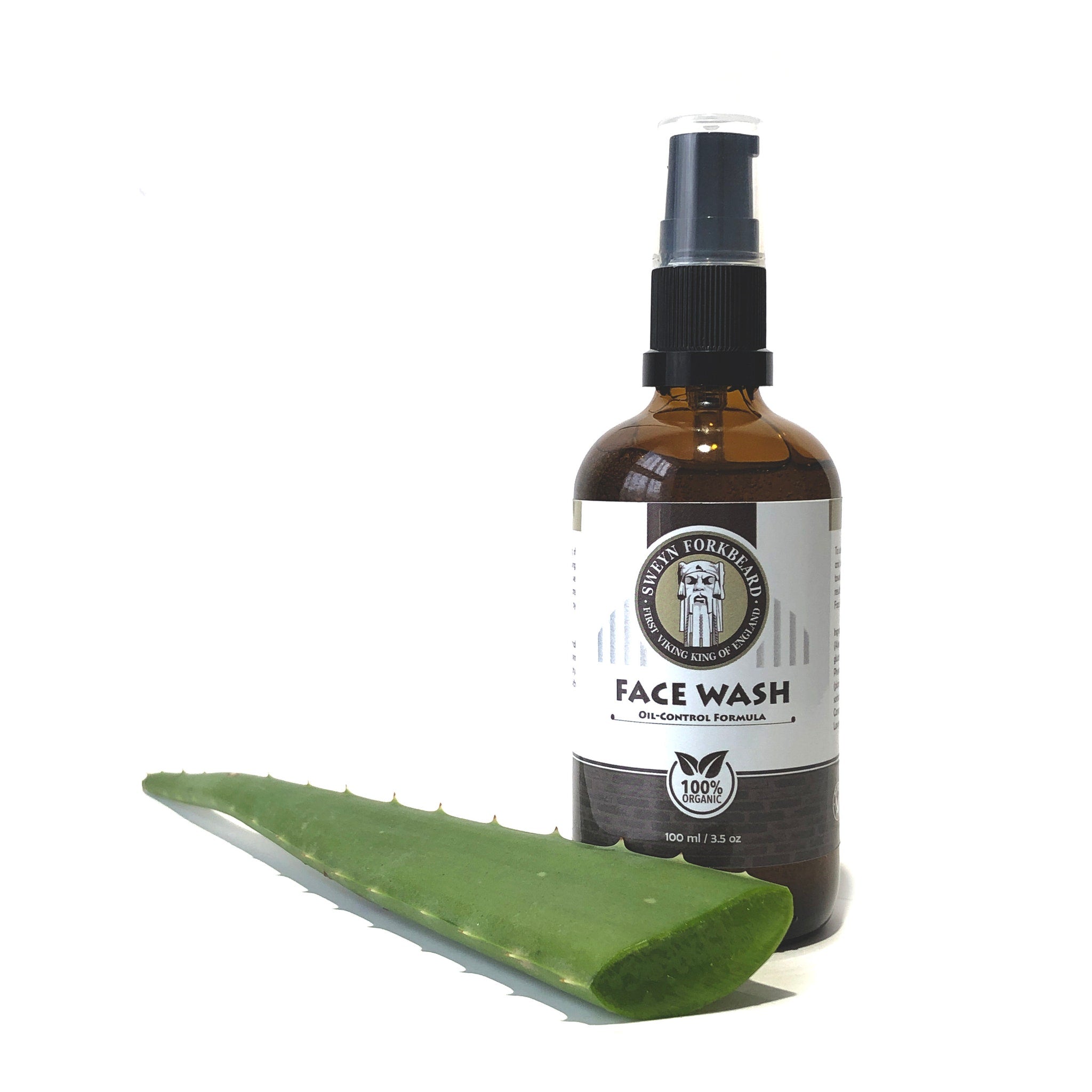 Face wash bottle with brown glass, black pump, and green aloe leaf next to it