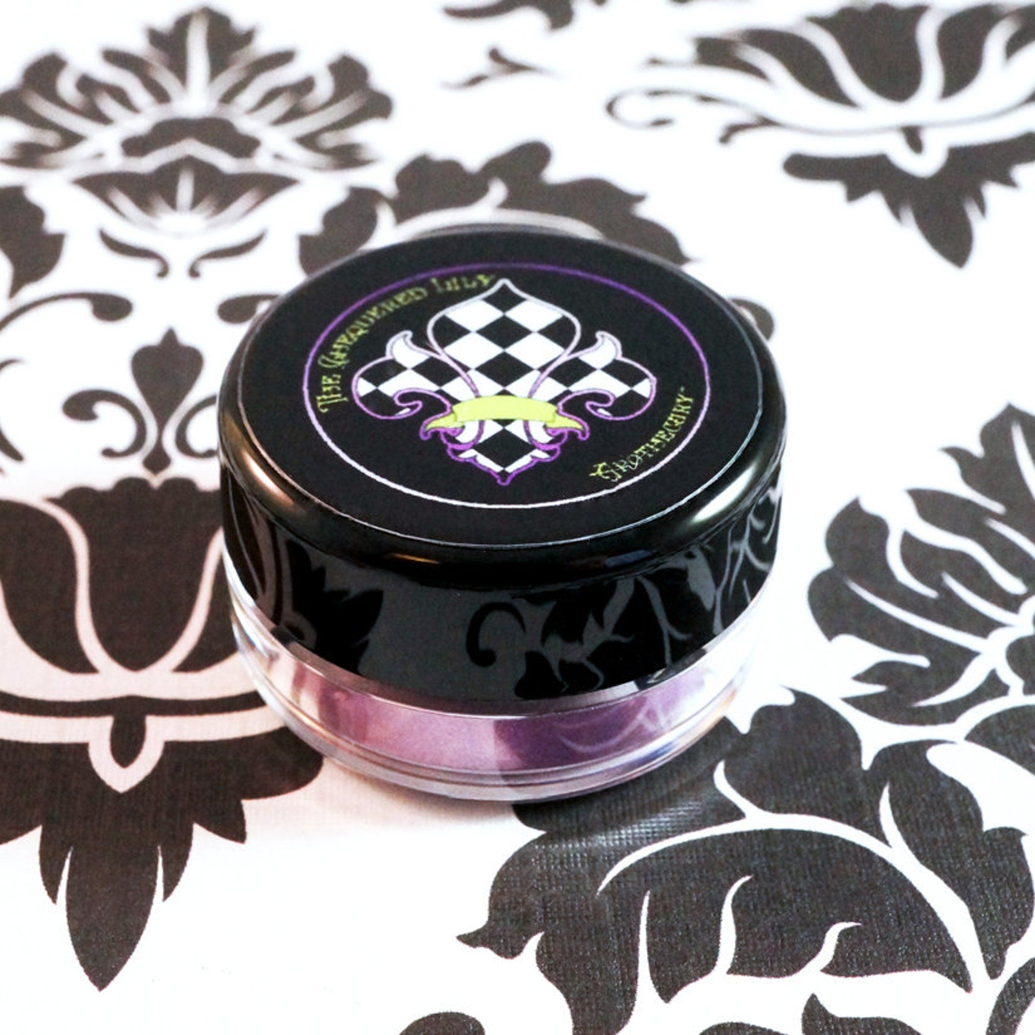 Black and white patterned jar with "The Gauquered Lily" text, and purple rim on floral background