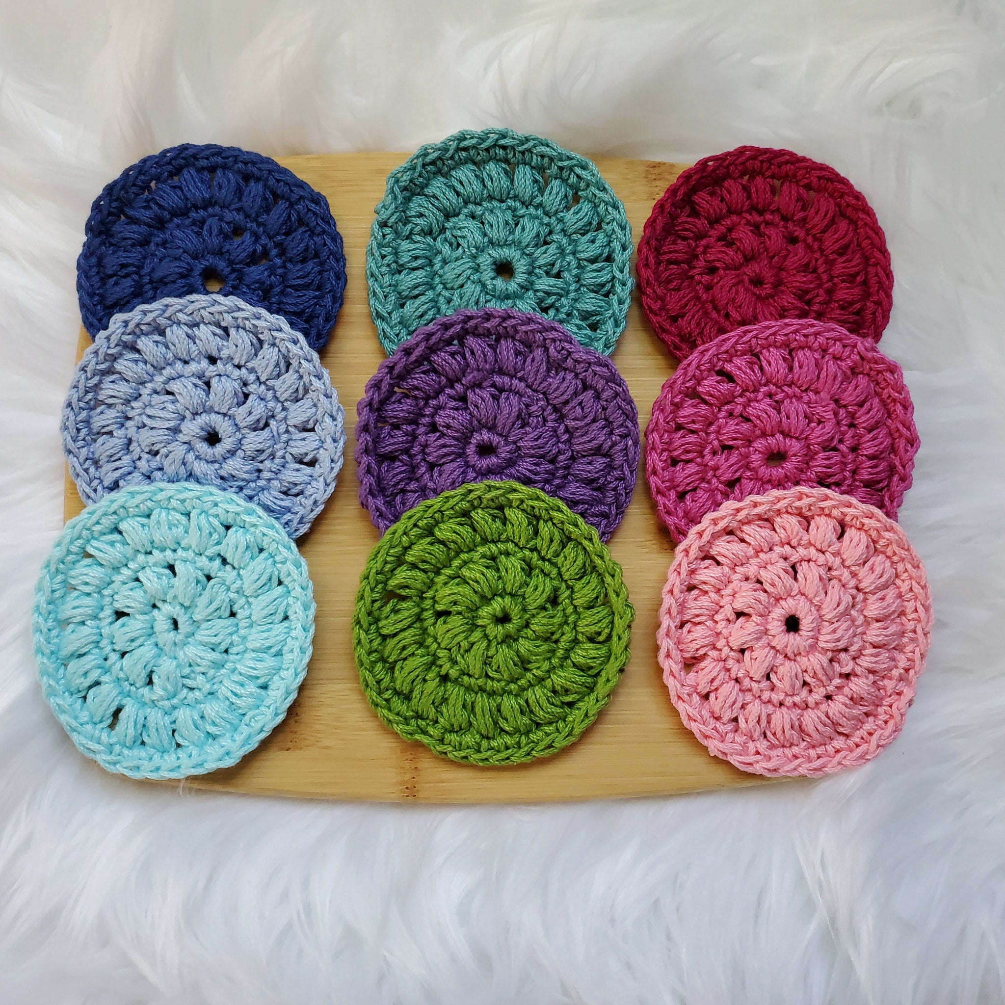 Crochet coasters in various colors, round cotton coasters displayed on a wooden board