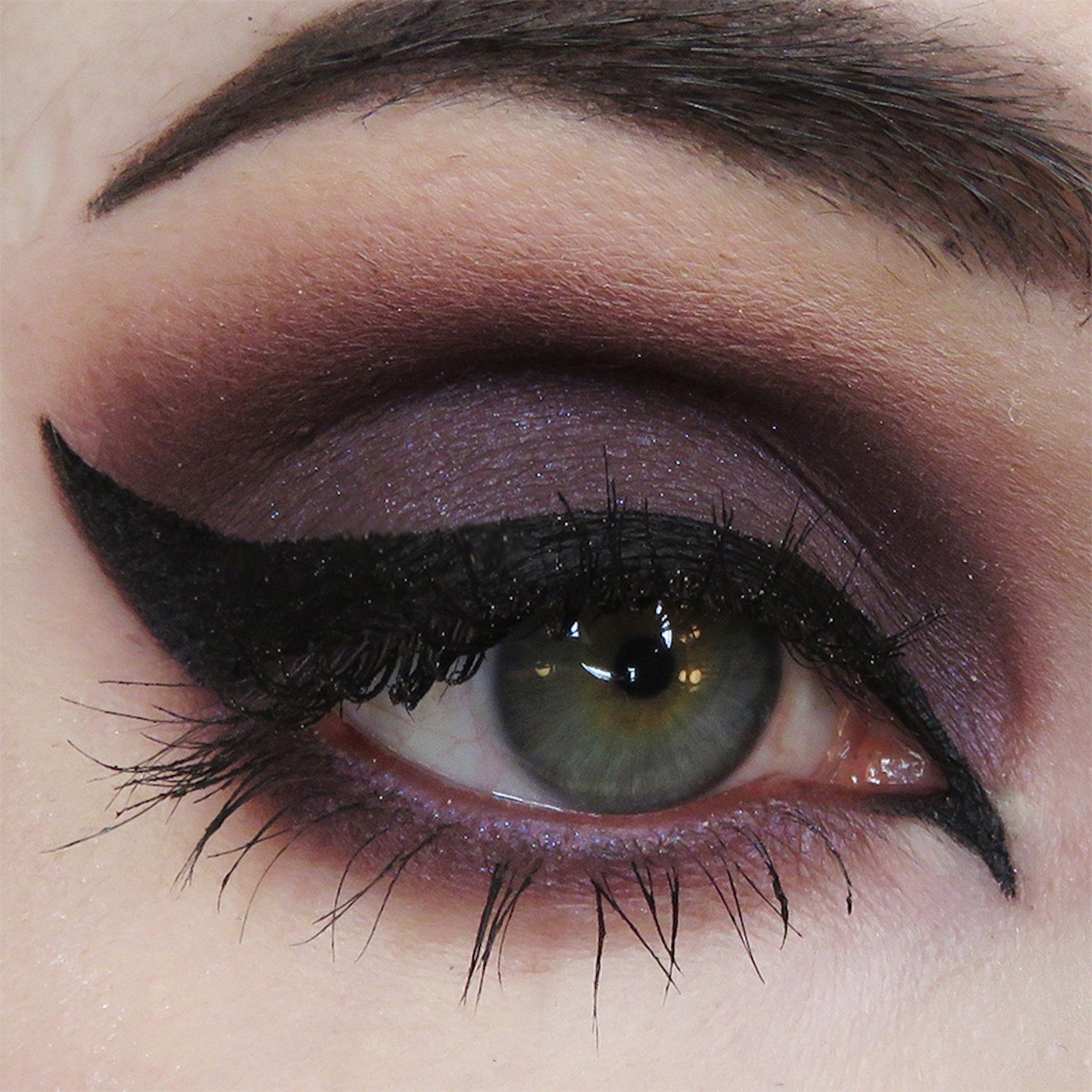 Eyeliner and eyeshadow makeup with black wing, purple eyeshadow, and dark eyelashes