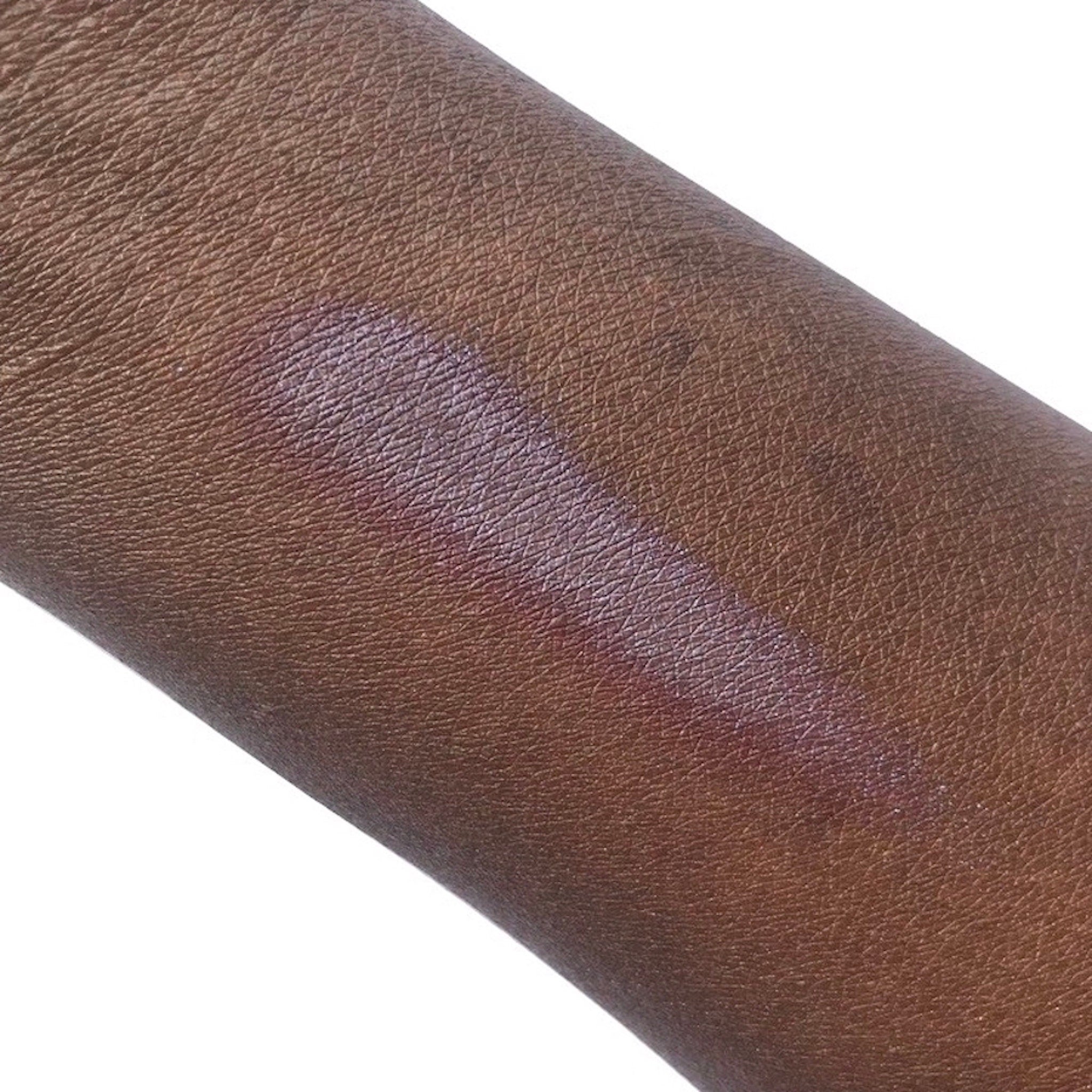 Skin swatch with purple and silver shimmer on dark brown skin, showing texture