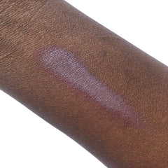 Skin swatch with purple and silver shimmer on dark brown skin, showing texture