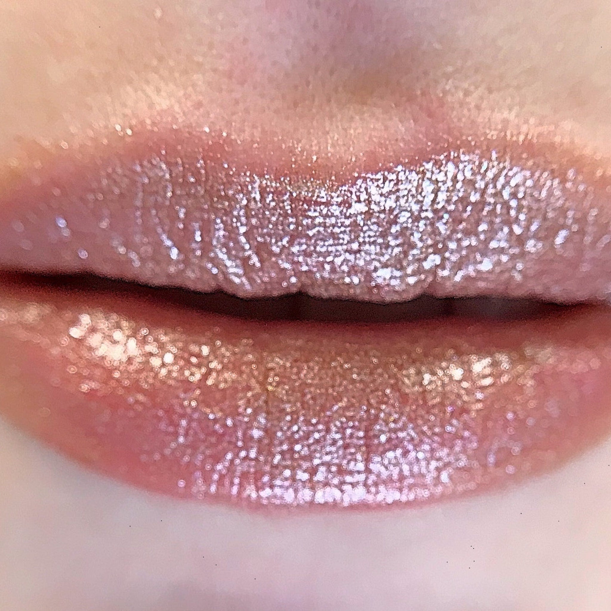 Lip gloss with shimmering pink color and glossy finish on lips