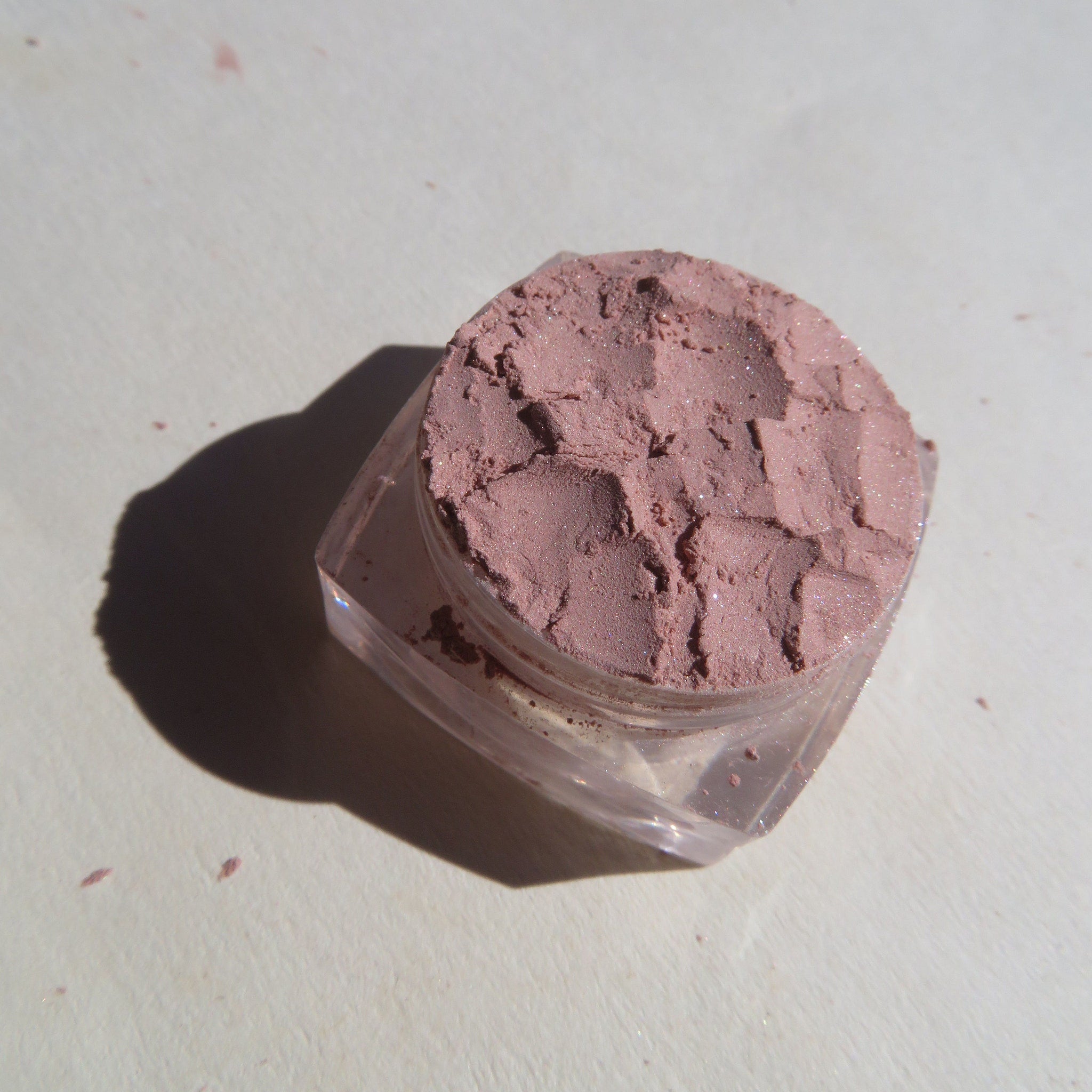 Close-up of sandy brown shimmer loose pigment eyeshadow with fine mineral sparkle in a small jar