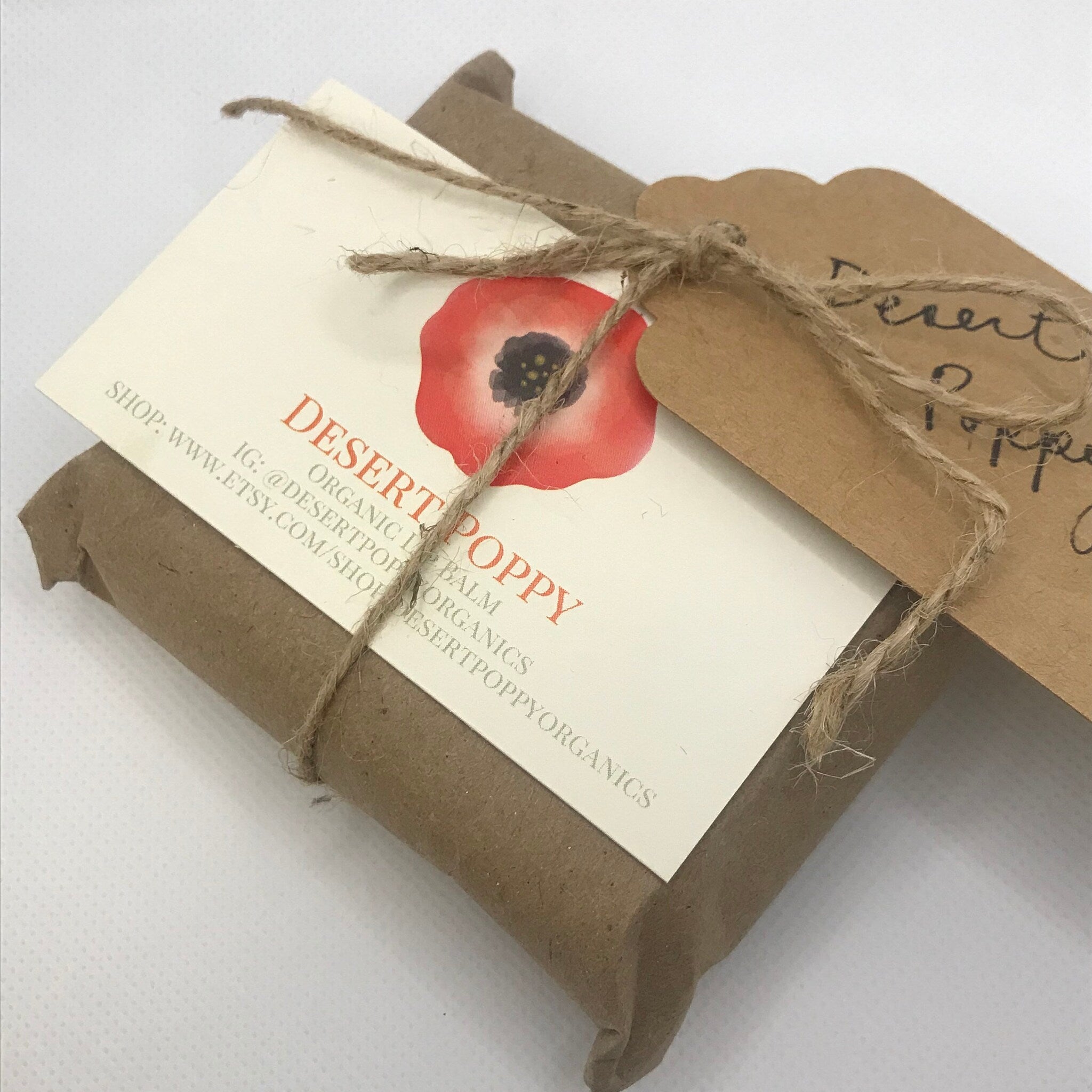 Desert Poppy lip balm wrapped in brown paper with twine and tags, Desert Poppy branding visible