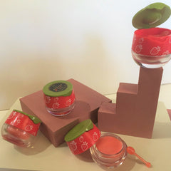 Lip balm jars with red lids, white strawberry pattern, and clear glass container