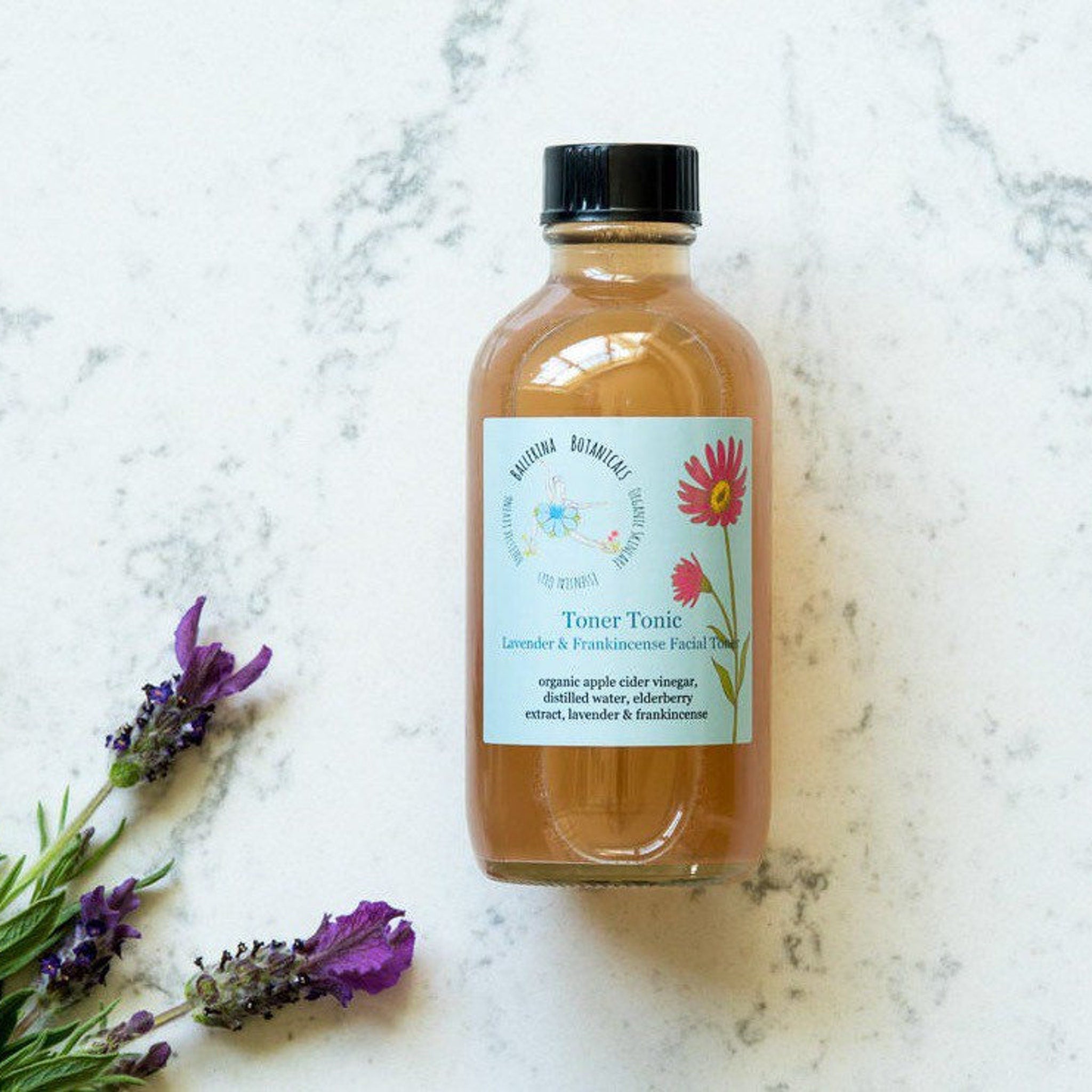 Toner Tonic bottle with brown liquid, black cap, and floral label on white marble surface