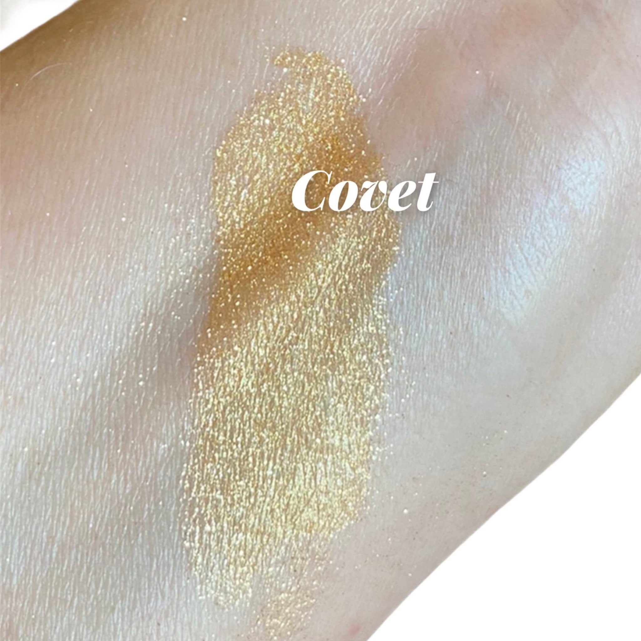 Close-up of gold glitter eyeshadow with shimmer particles in a small round jar, showcasing intense metallic luster
