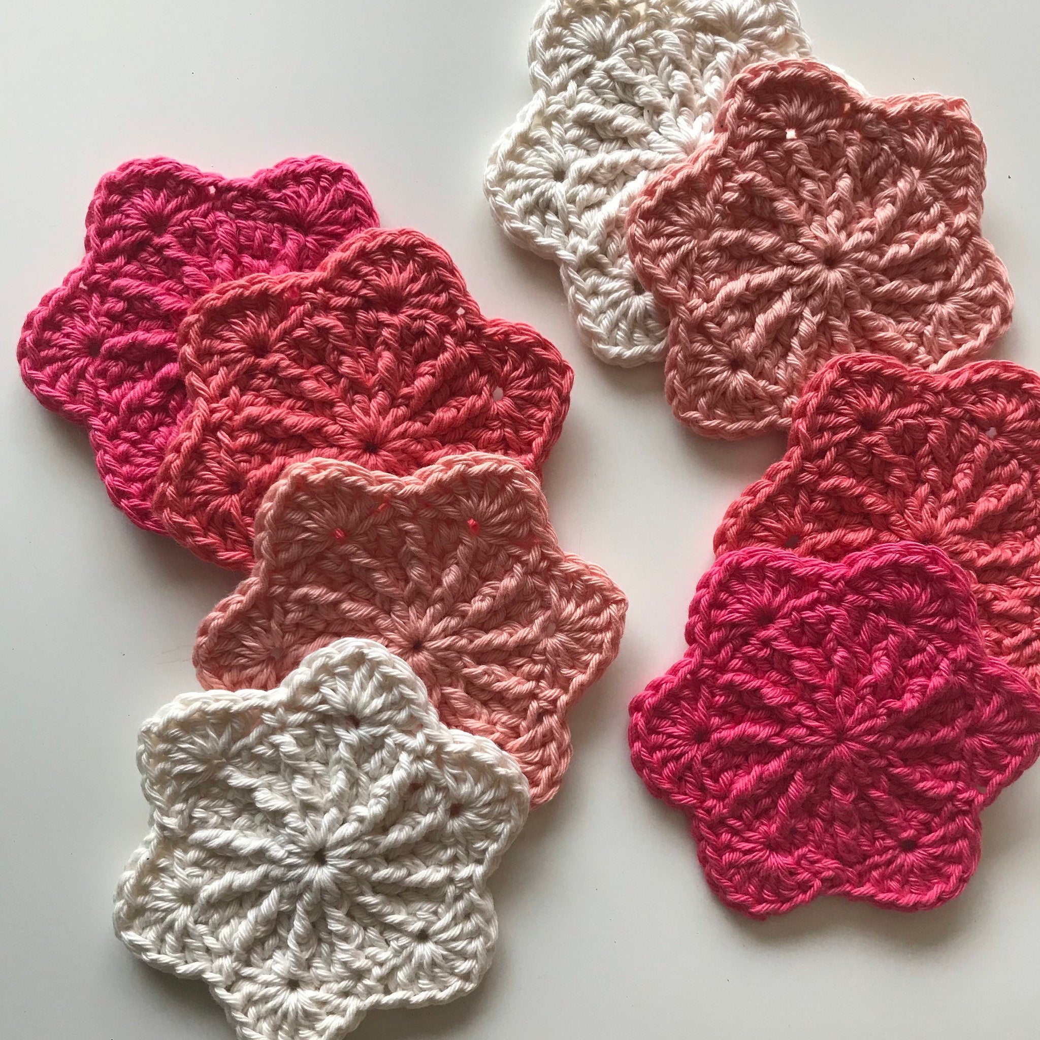 Crochet coasters in pink, white, and peach colors with starburst pattern design