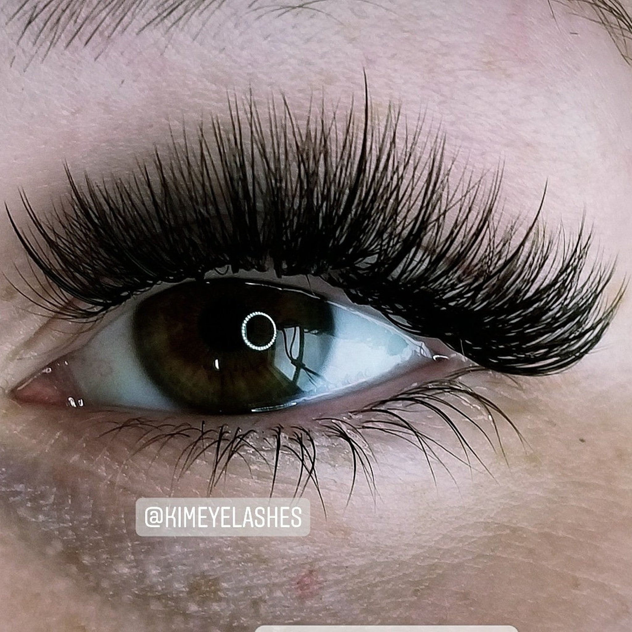 Eyelash extensions with black, long, layered lashes and brown eye, by @KIMEYELASHES