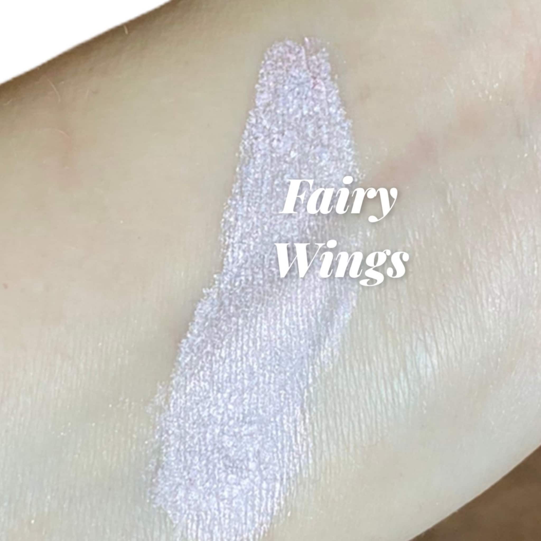 Fairy Wings" text with light purple shimmer on skin, showing color and texture of product
