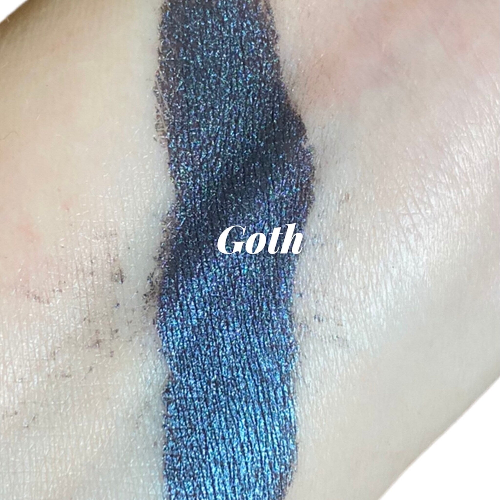 Close-up of dark navy blue eyeshadow with shimmering metallic luster in compact pan