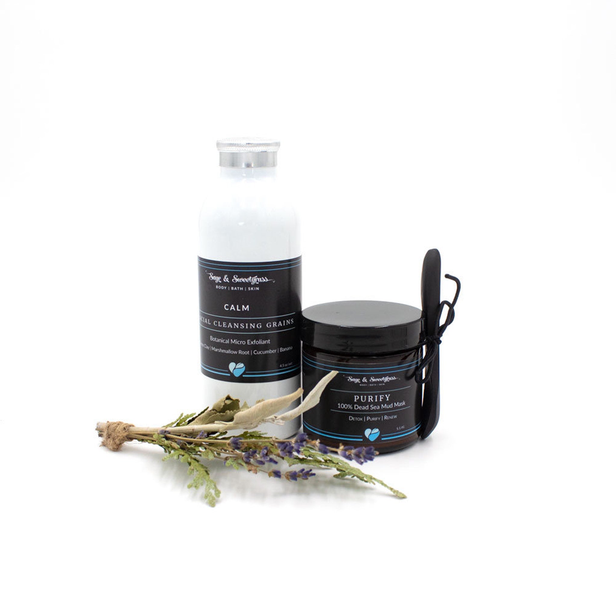 Skincare products with white and black labels, Sage & Sweetgrass branding, and dried flowers and herbs in the foreground