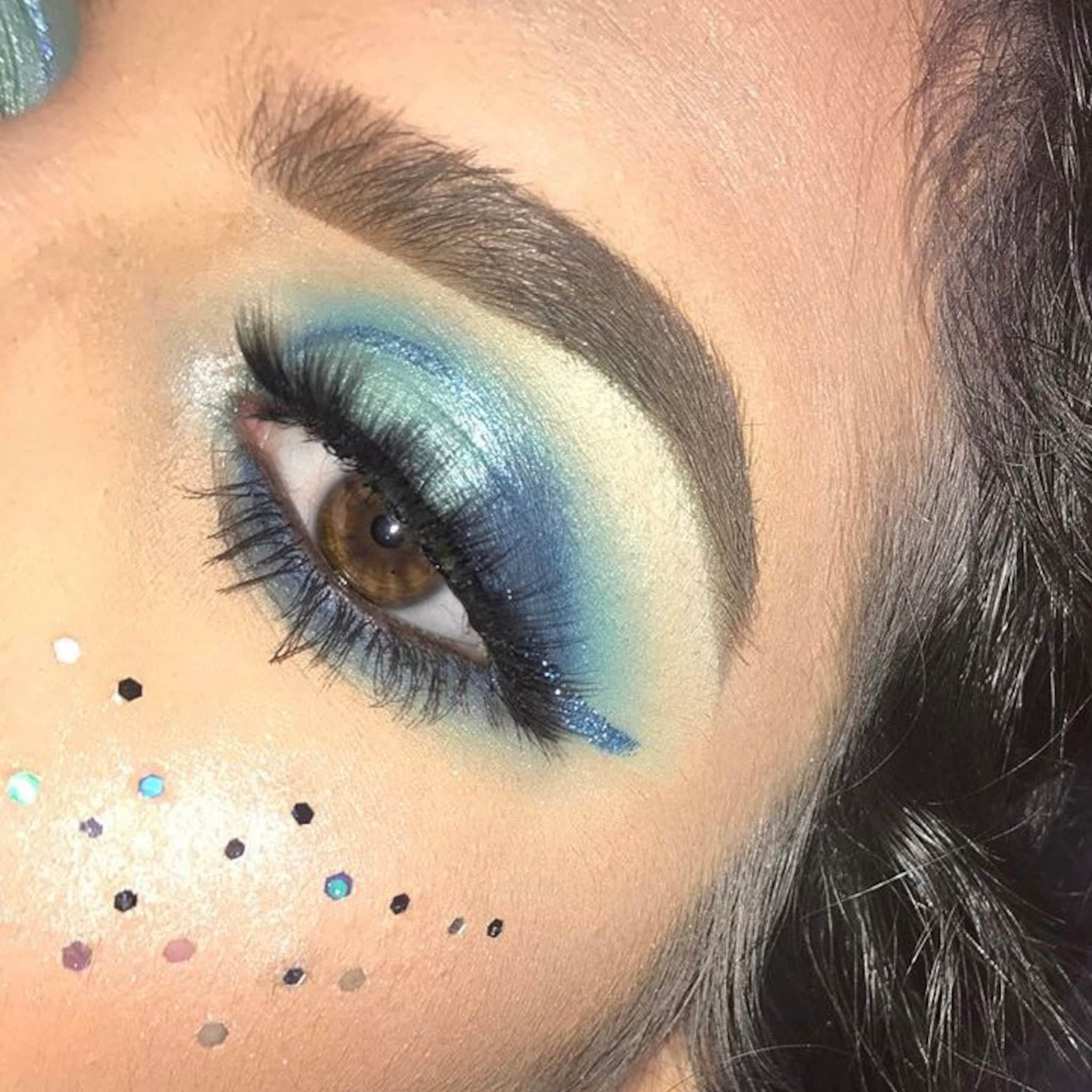 Eye makeup with blue eyeshadow, glitter eyeliner, and brown eye, close-up view