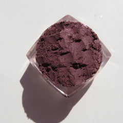 Eyeshadow powder, dark purple with shimmer, in clear plastic container, top-down view