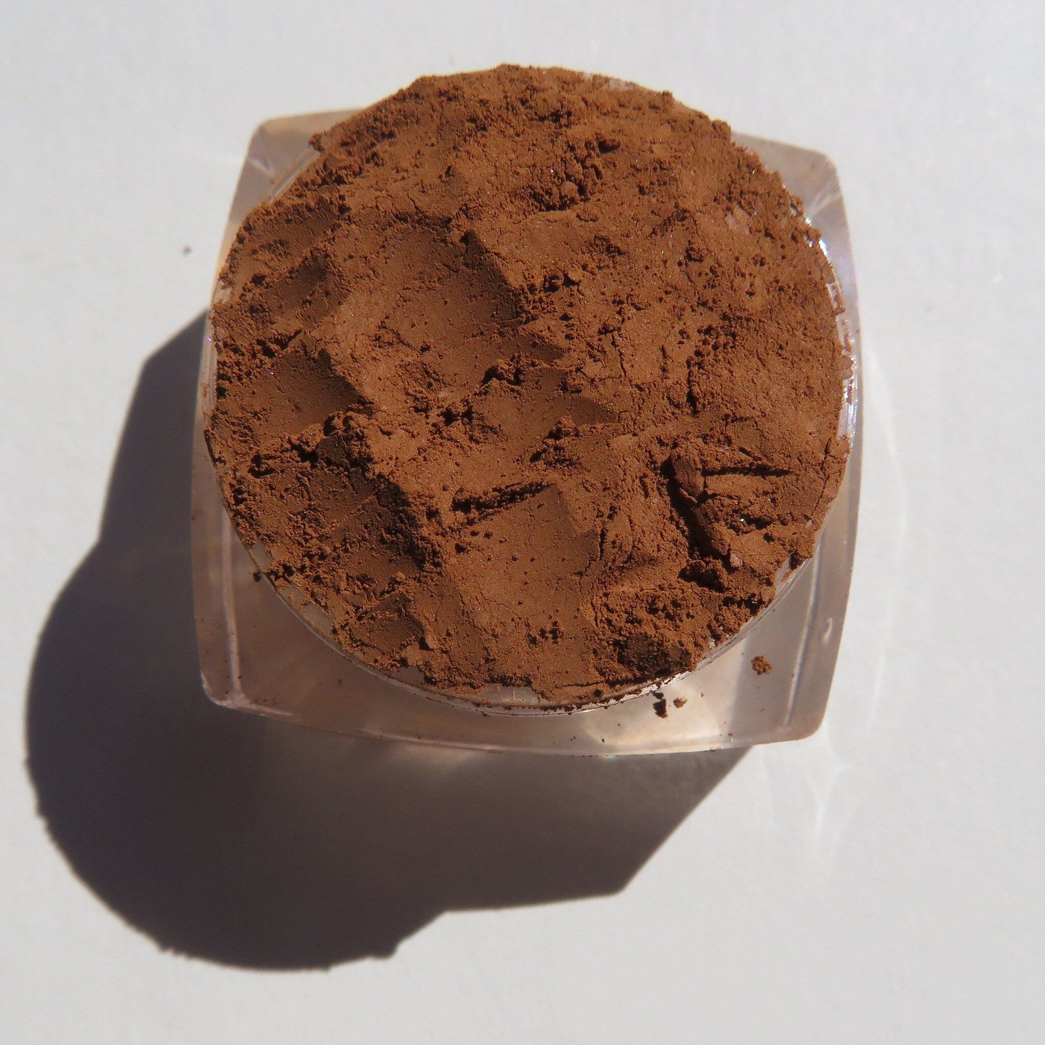 Hand applying sandy brown loose mineral eyeshadow with a brush for a soft matte finish