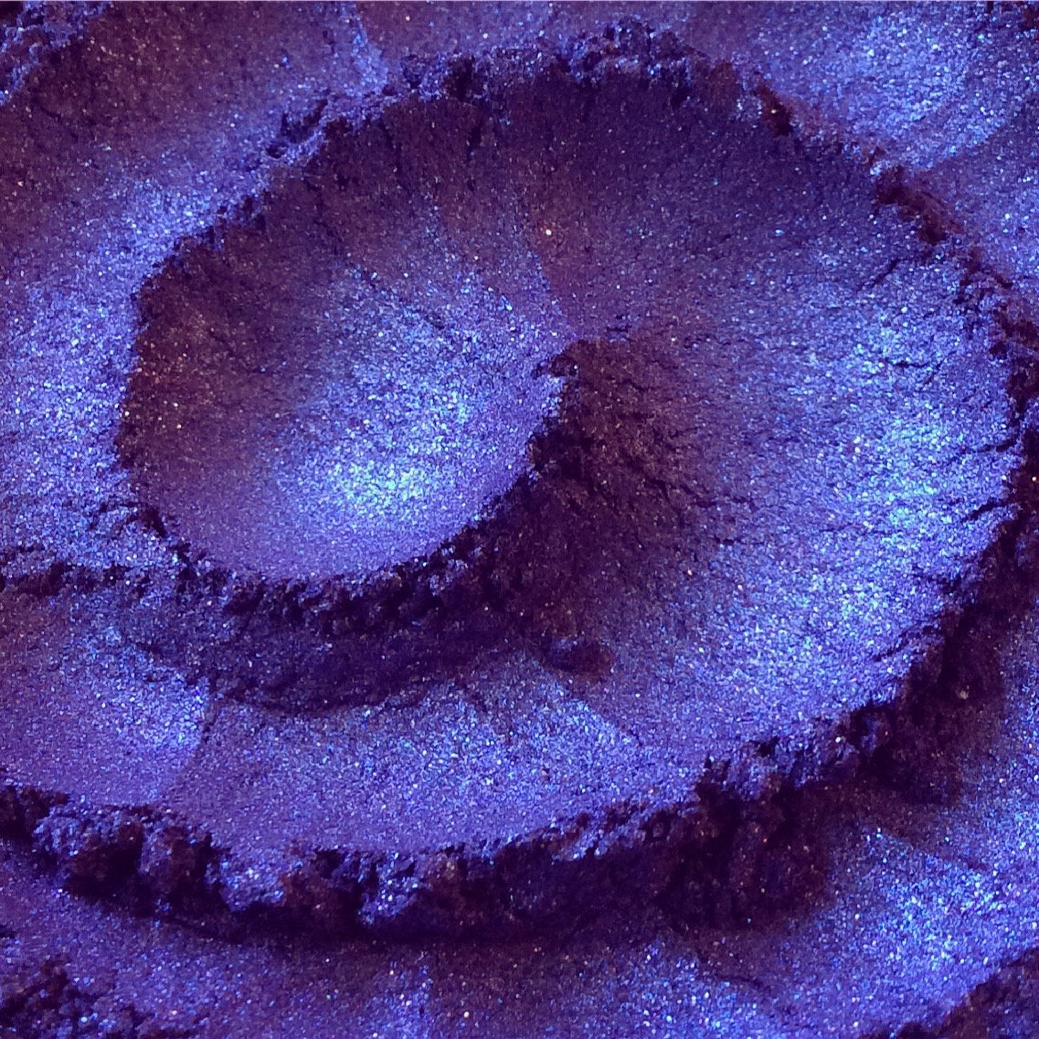 Open jar of African Violet loose pigment eyeshadow with metallic indigo shift and sparkling glitter particles