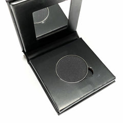 Side view of jet black mineral eye shadow compact showing matte paperboard texture and hinge detail