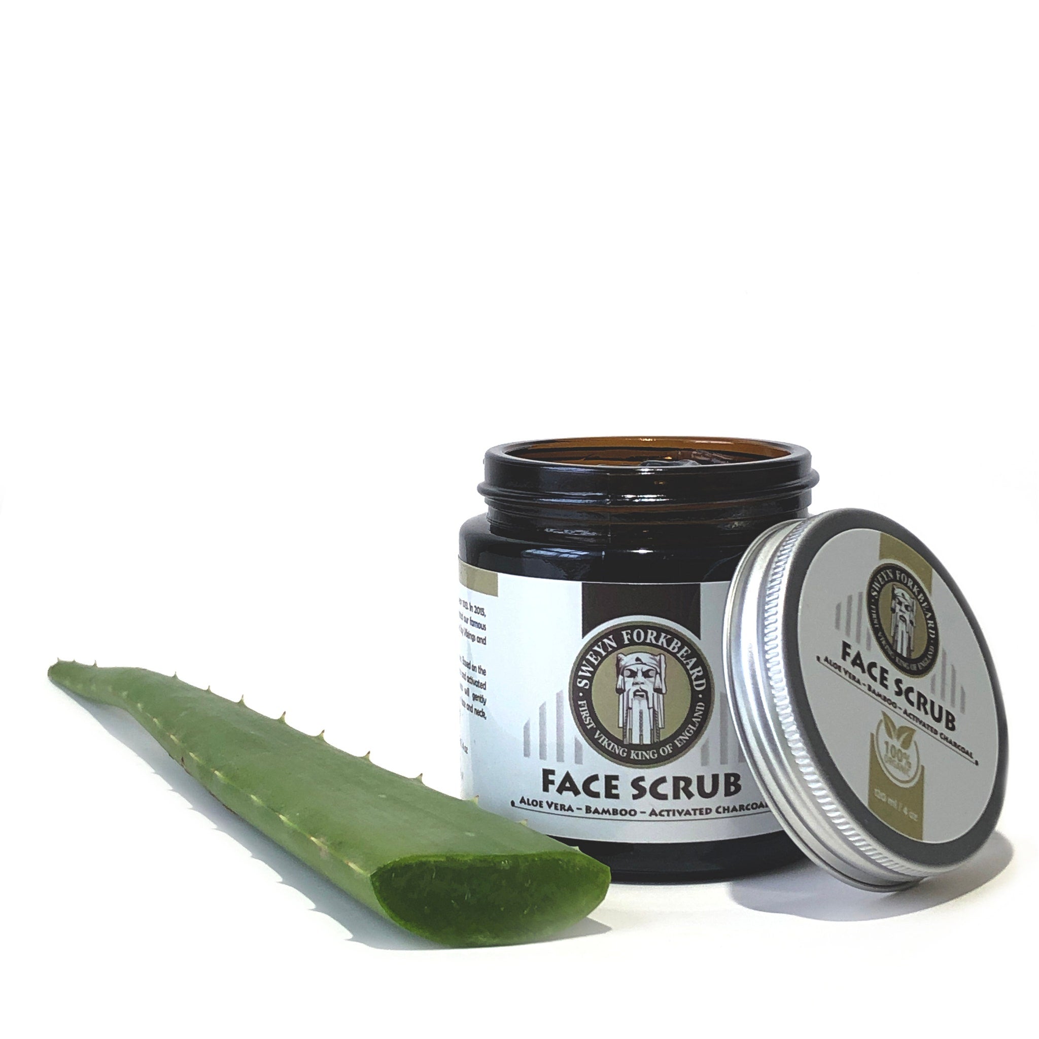 Face scrub jar with brown glass, silver lid, and green aloe vera leaf next to it