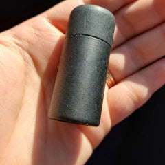 Black cylindrical container with textured finish held in hand