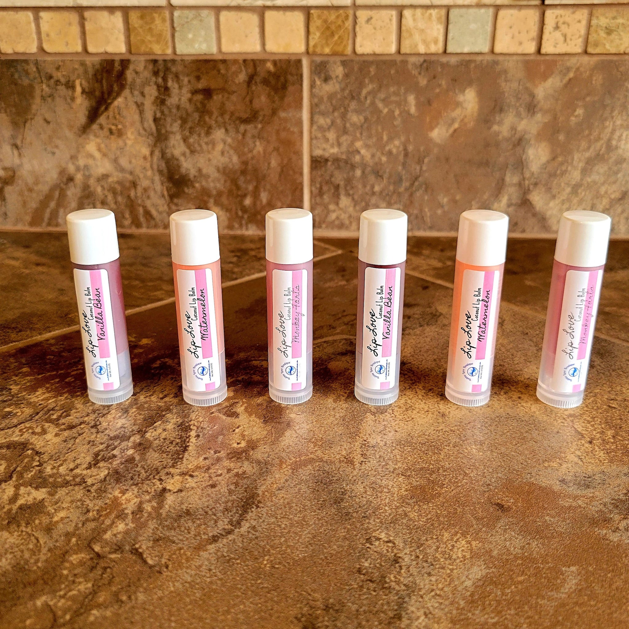 Lip balm tubes with white caps, pink labels, and various colored balm visible, Lip Love brand