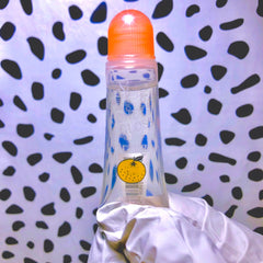 Clear plastic bottle with orange cap, blue dots, and Kai Kosmetics logo in hand