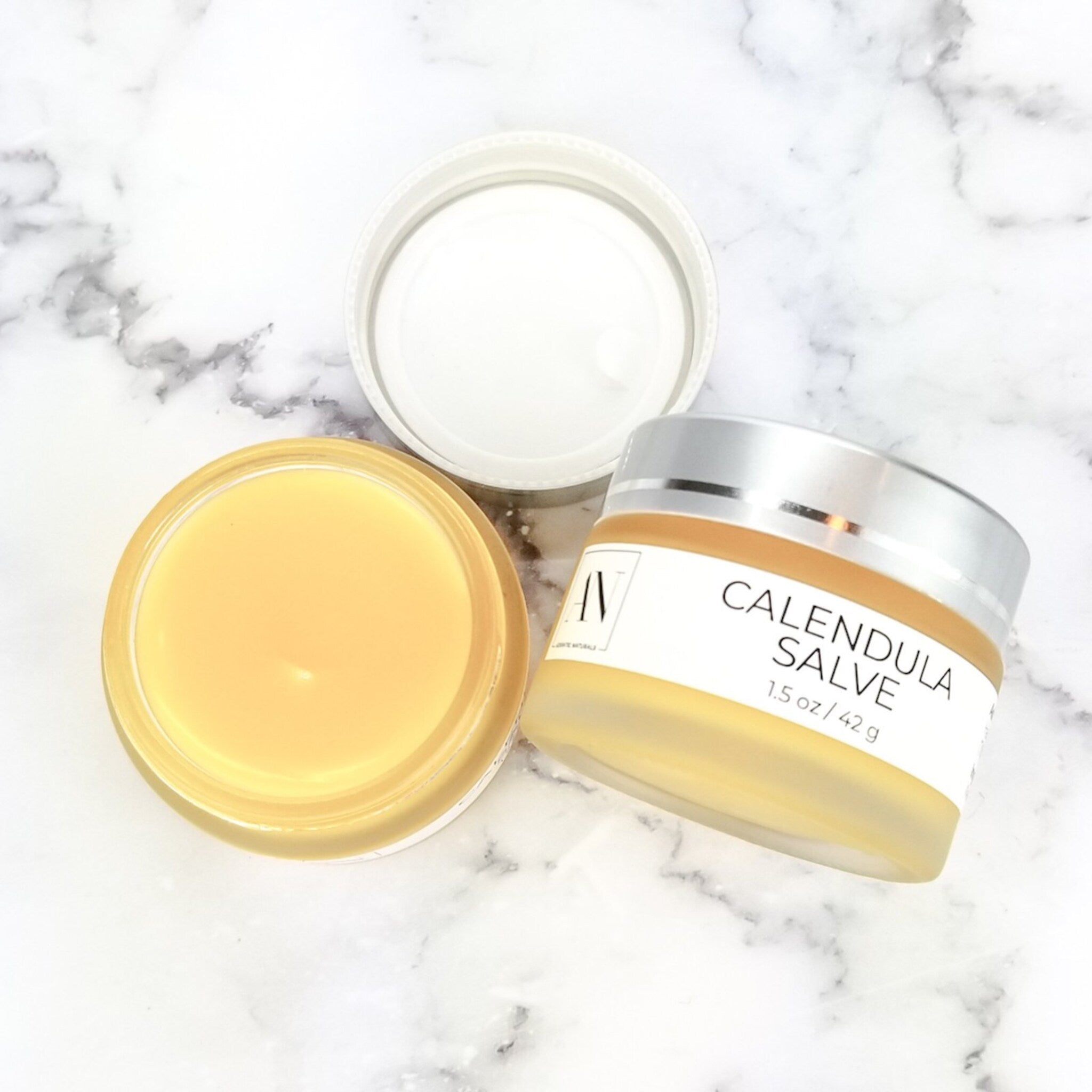 Calendula Herbal Salve, yellow salve in glass jar with silver lid, Adriatic Naturals text visible
