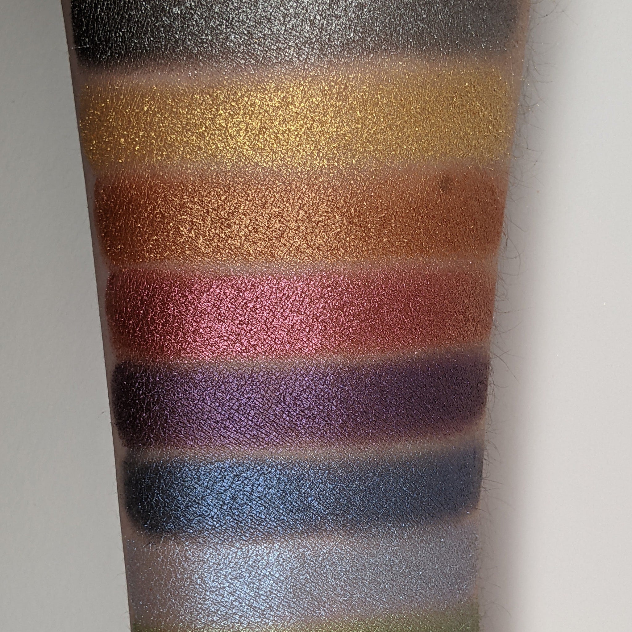 Close-up of fingertips applying bronze shimmer eyeshadow to eyelid with soft blending motion
