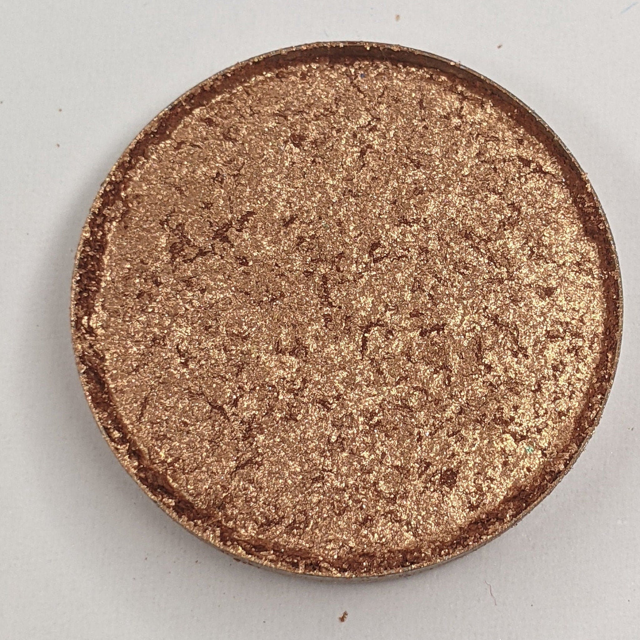 Bronze shimmer pressed eyeshadow in round compact with vegan label, showcasing warm metallic finish