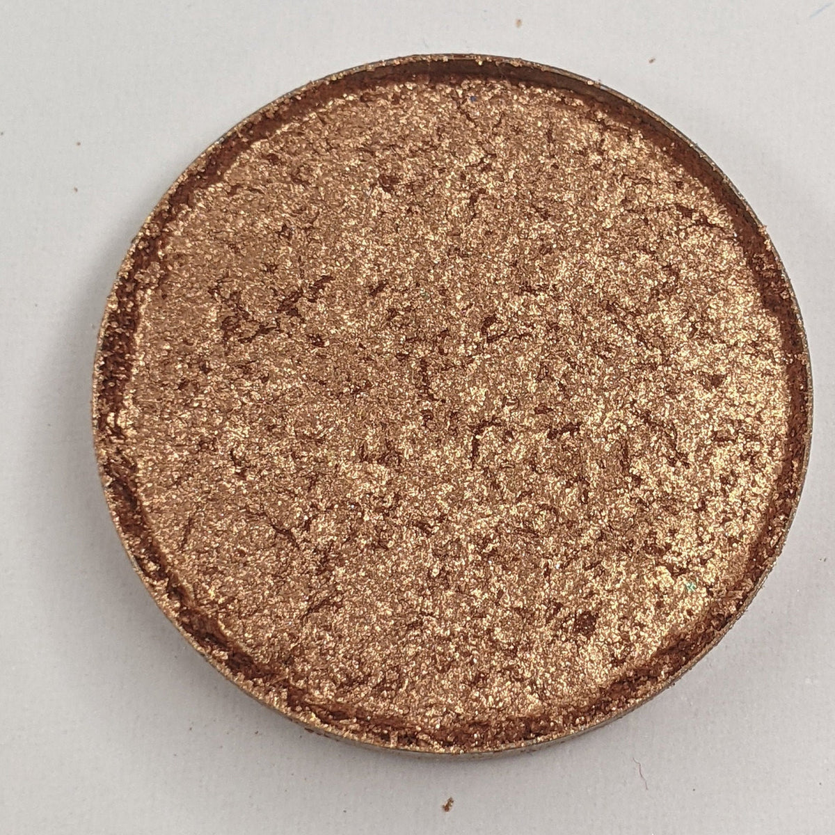 Bronze shimmer pressed eyeshadow in round compact with vegan label, showcasing warm metallic finish