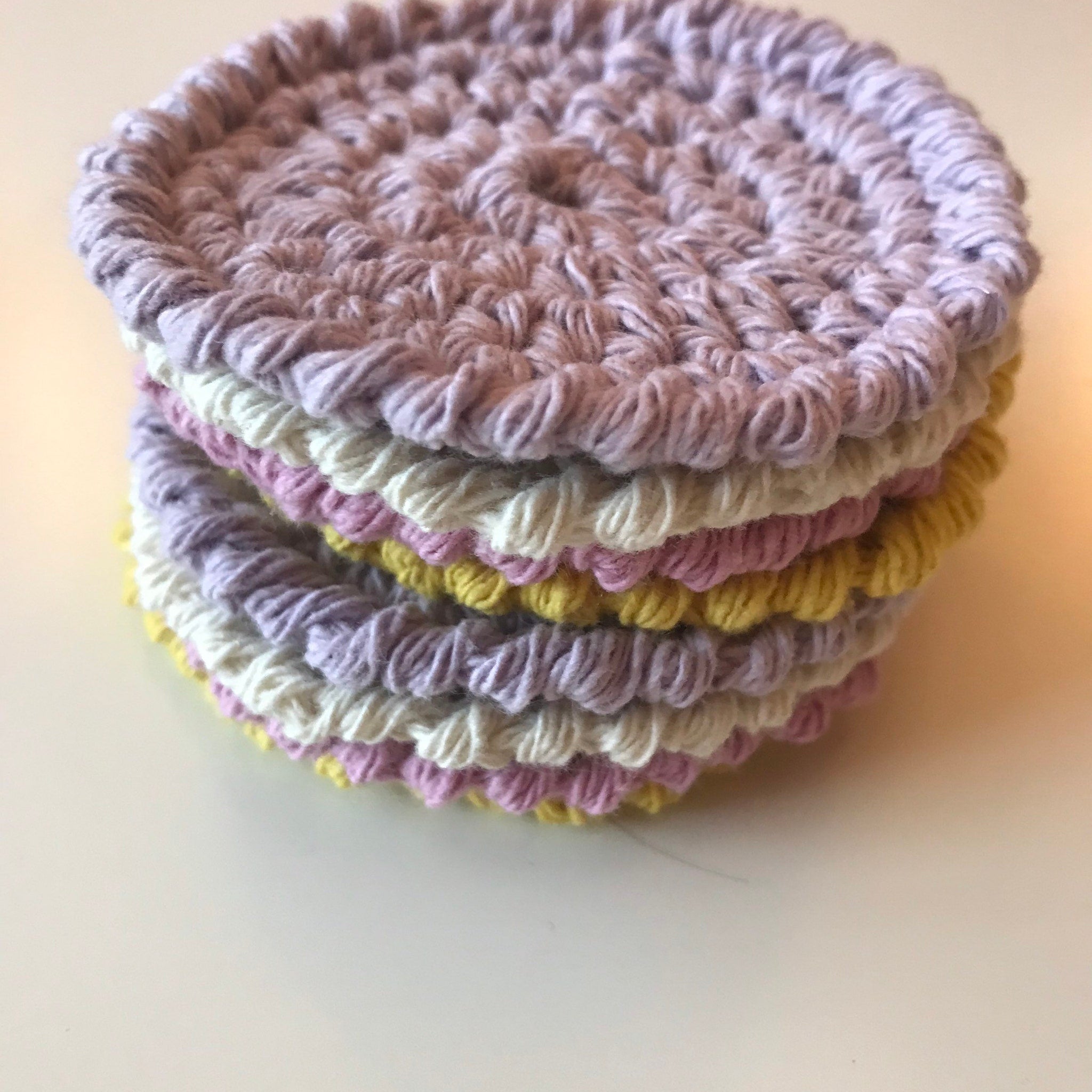 Crocheted coasters in pastel colors, stack of round, textured cotton material