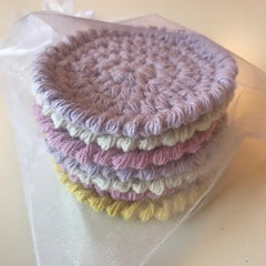 Reusable cotton pads in pastel colors with a crocheted pattern, wrapped in sheer white fabric
