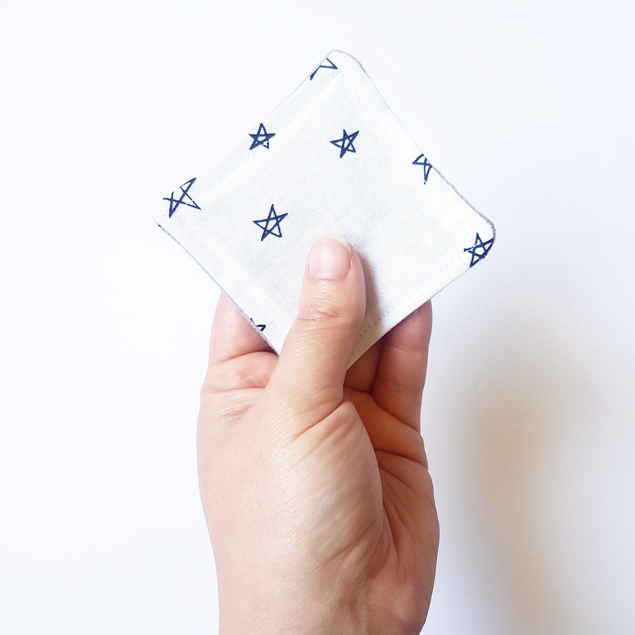 Square white cloth with blue star pattern, held in hand