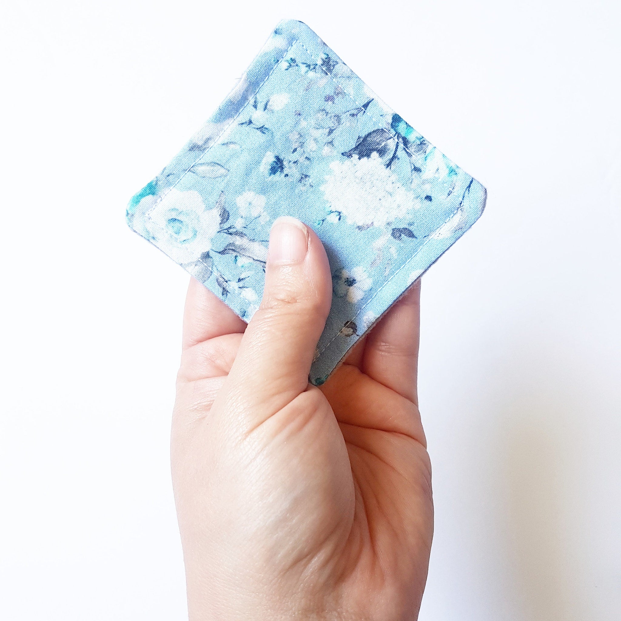 Coaster, blue floral fabric, square shape, held in hand