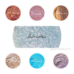 Hand applying iridescent chameleon loose pigment eyeshadow with fingertip, showcasing color-shift effect on eyelid.