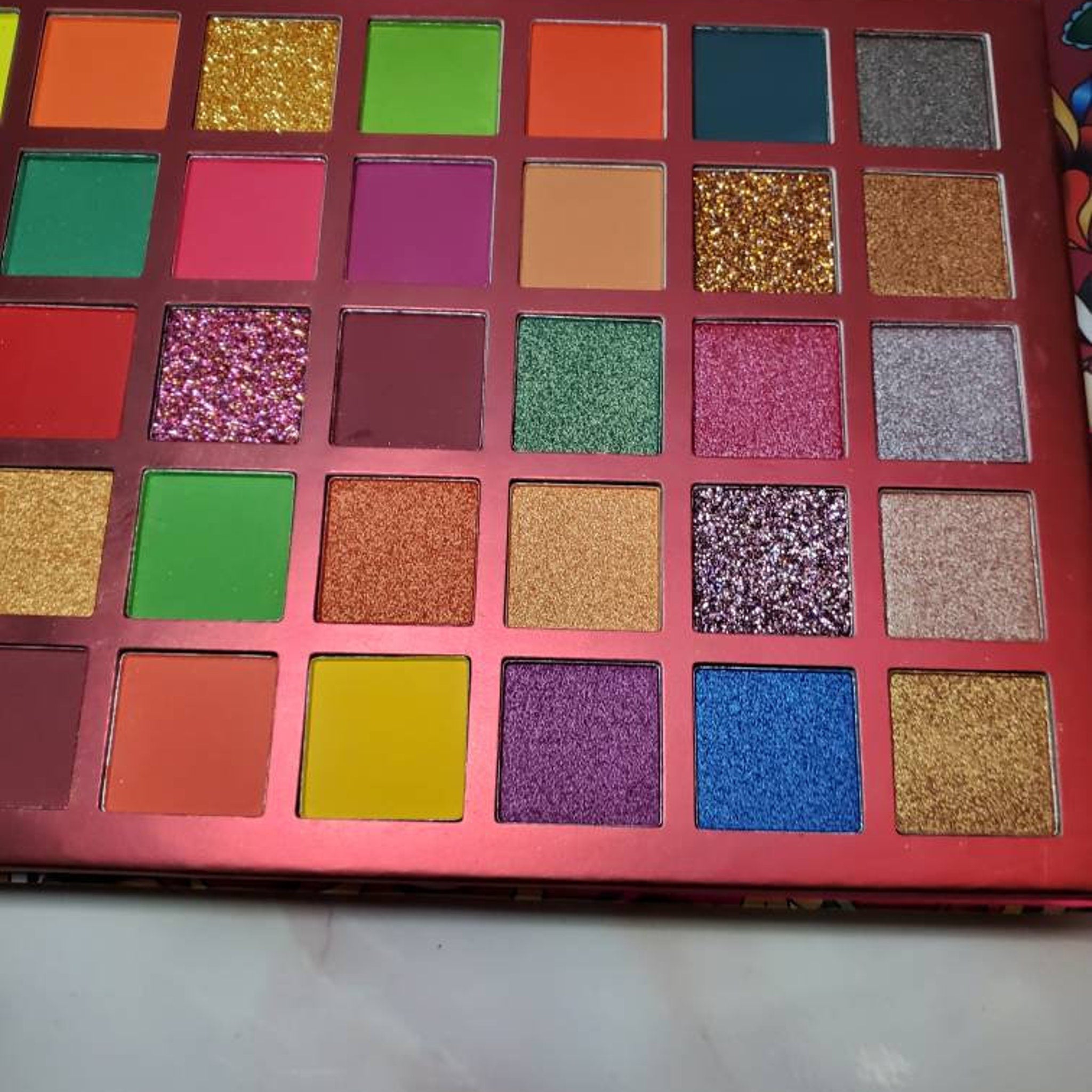 Side view of MI CORAZON eyeshadow palette showing sleek black compact with gold trim and visible shade range