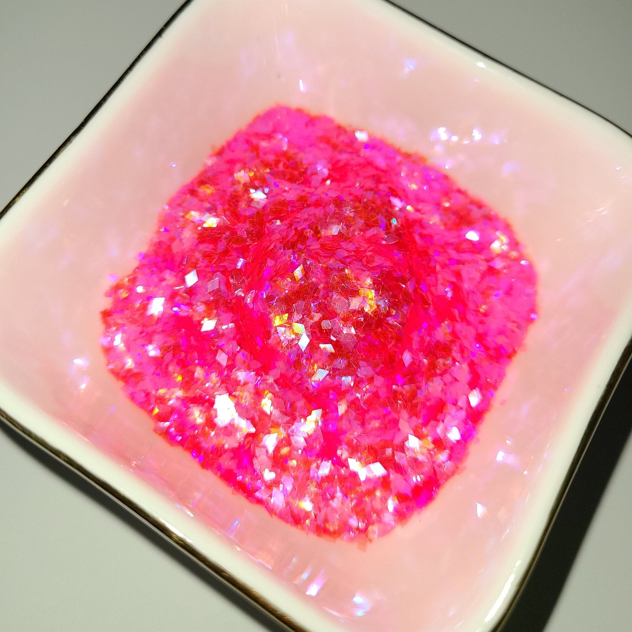 Pink glitter in a pink square dish with gold trim, close-up shot