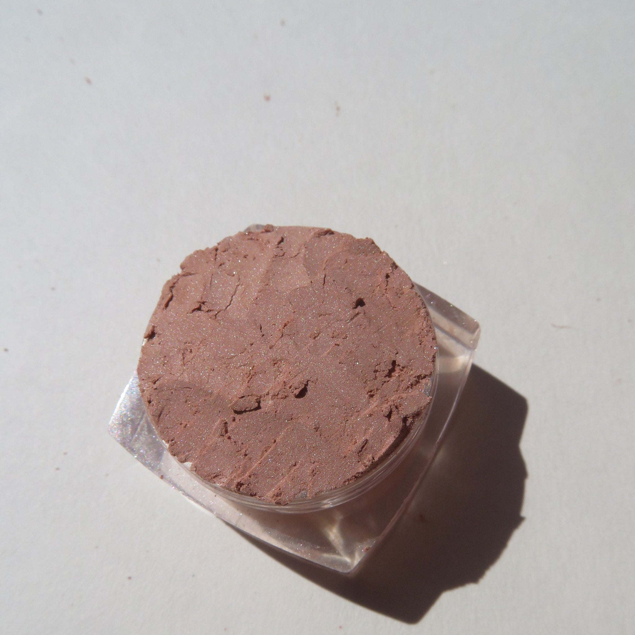 Side view of matte brown loose mineral eyeshadow in a sifter jar with vegan and cruelty-free label visible