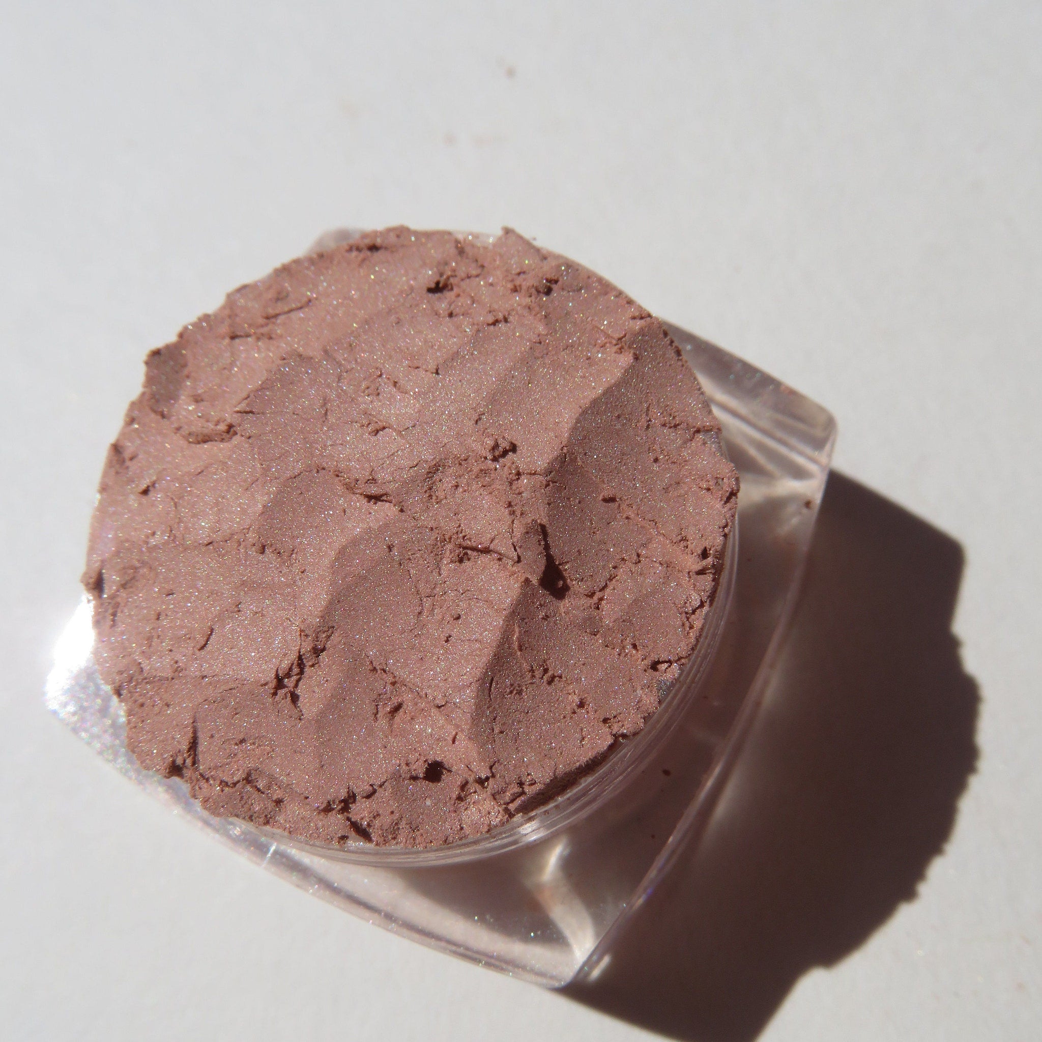Close-up of matte brown loose mineral eyeshadow powder with warm coffee latte tones in eco-friendly packaging
