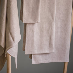 Linen napkins, beige color, woven texture, folded on a wooden rack