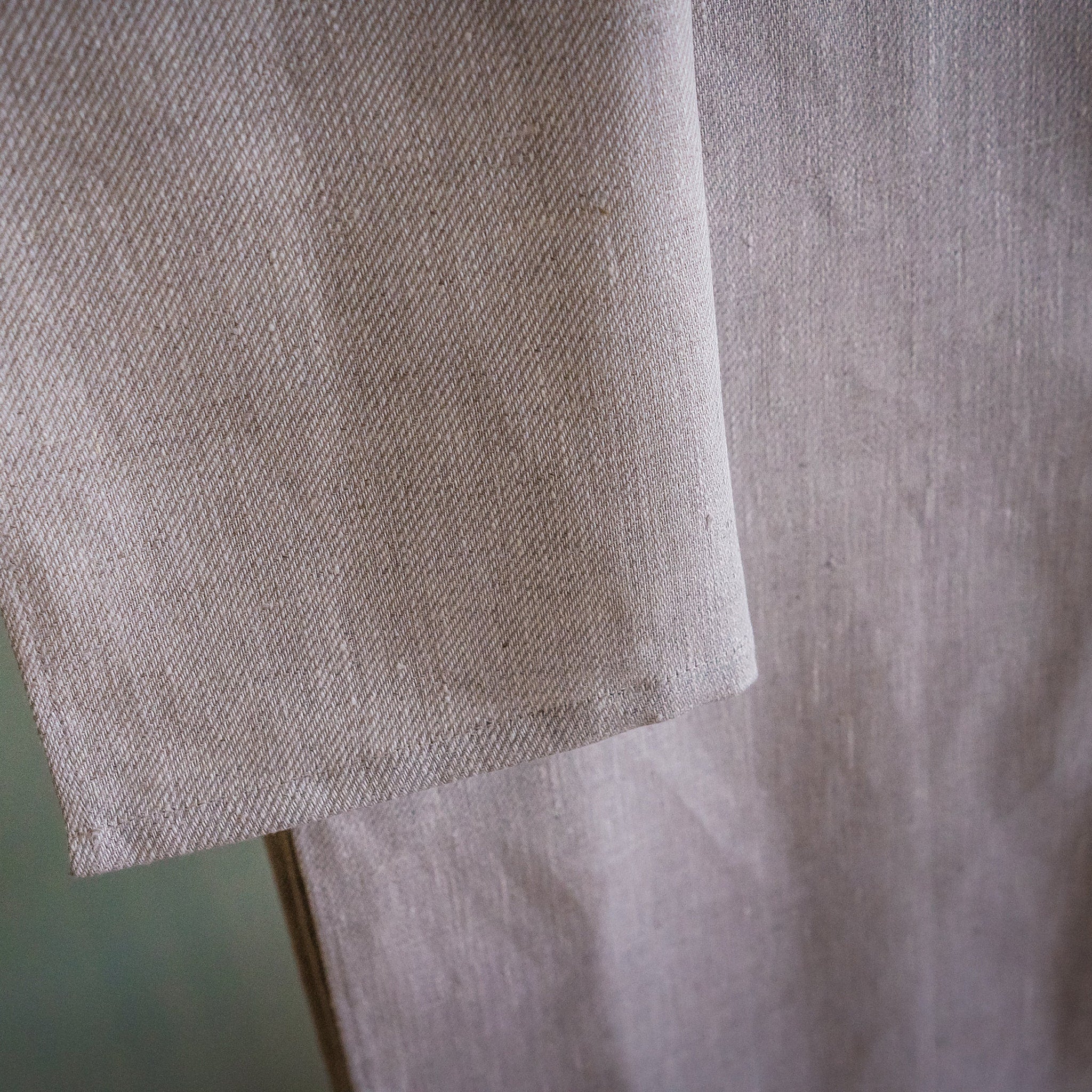 Beige linen fabric with woven texture and folded edge detail