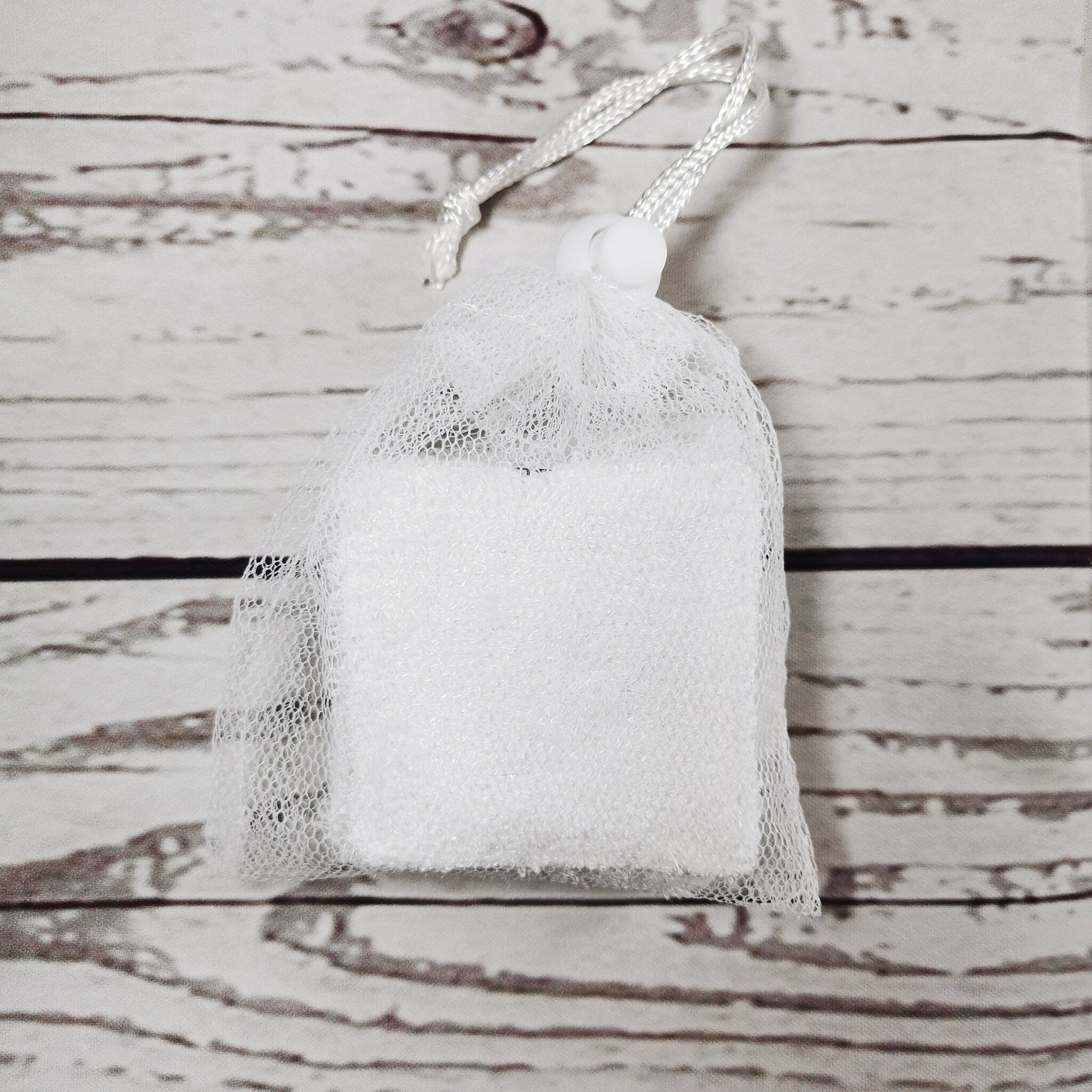 White mesh bag with white drawstring and white rectangular object inside