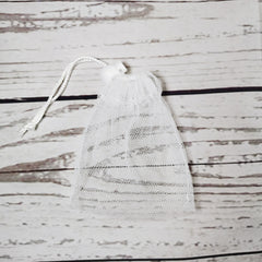 Soap saver bag, white mesh material with drawstring closure, on wooden background
