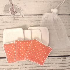 Reusable face pads with white terrycloth, coral polka dot pattern, and a mesh bag for storage