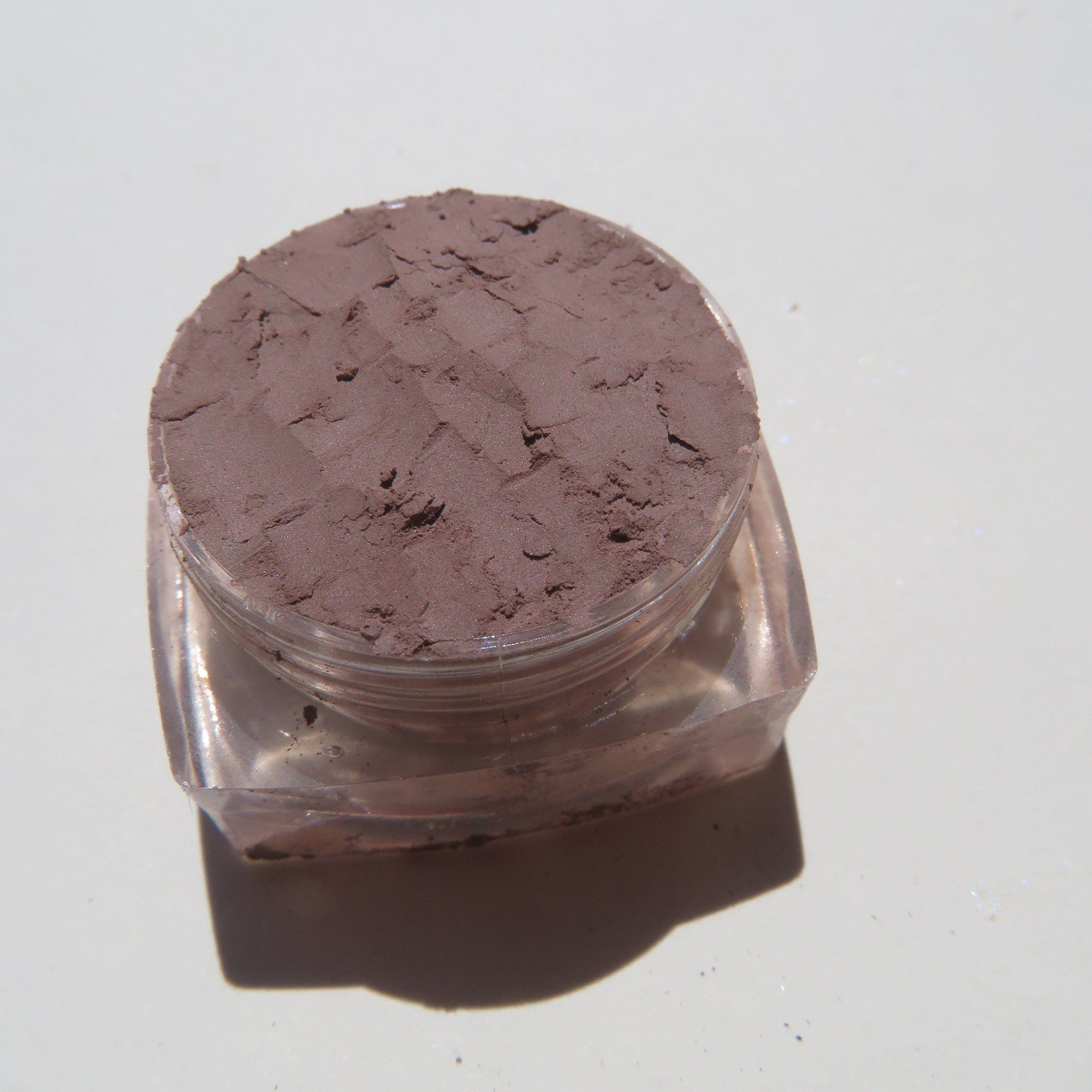 Close-up of matte taupe brown loose mineral eyeshadow with fine powder texture in eco-friendly packaging