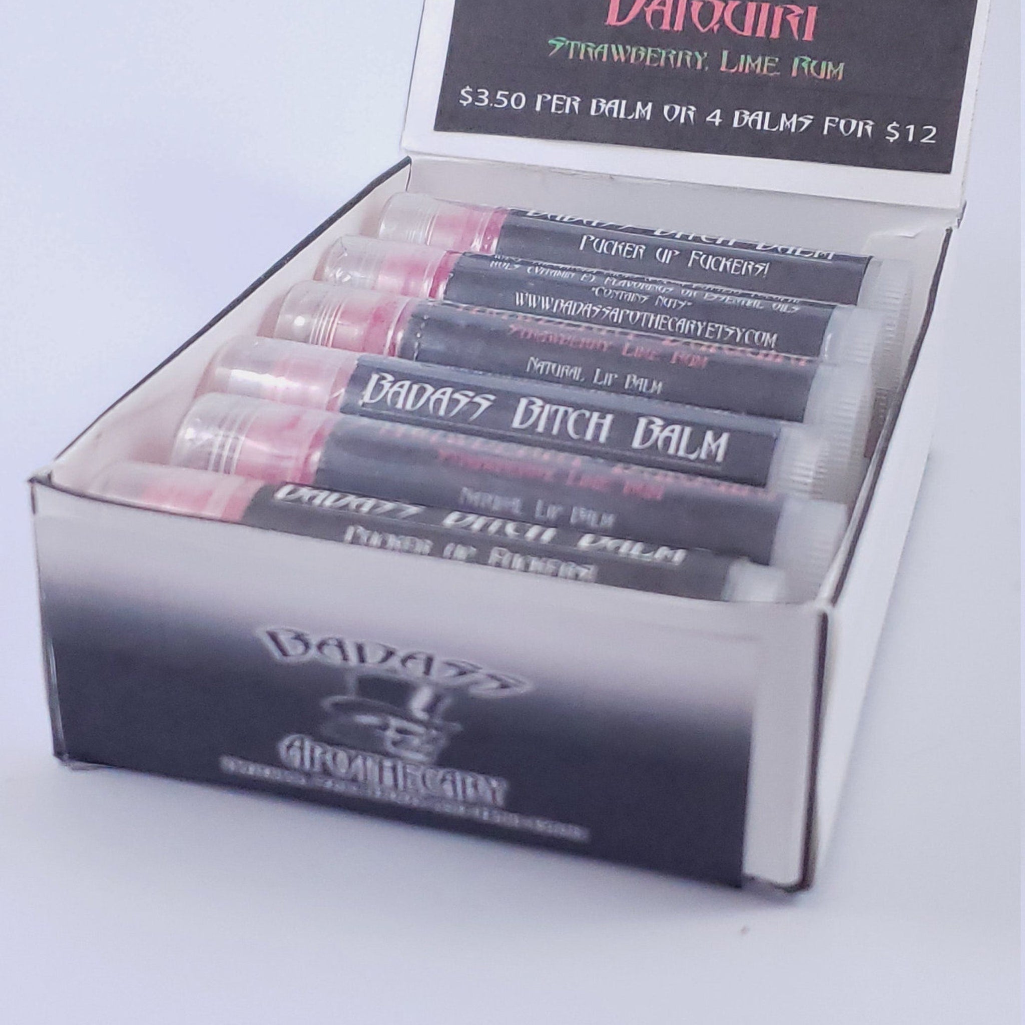 Lip balm tubes in a white box with black text and pink balm visible in the tubes BADASS AROMATHERAPY brand