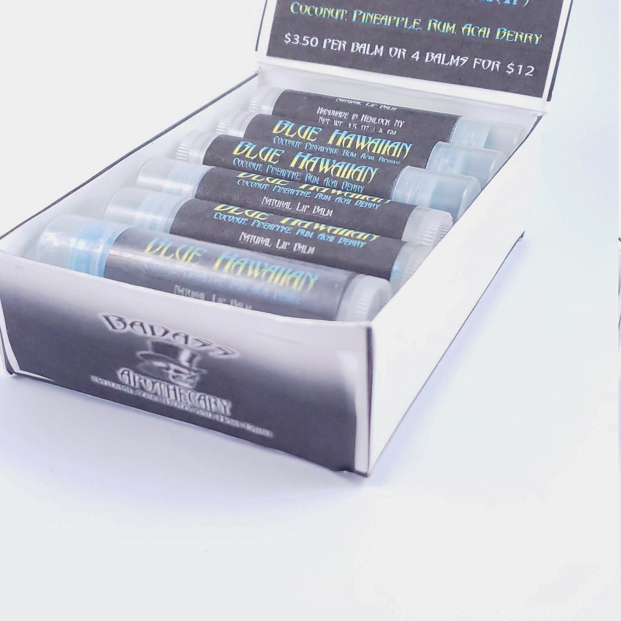 Lip balm tubes with black labels, clear caps, and "Blue Hawaiian" text in a box
