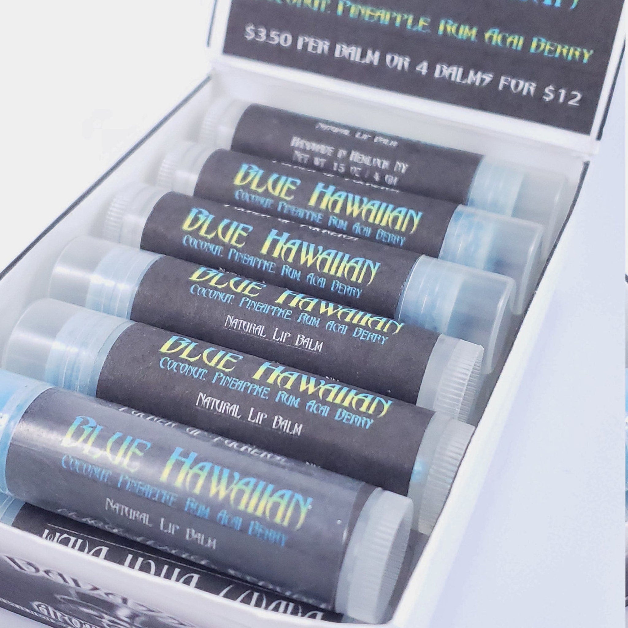 Lip balm tubes in a white box, black paper with Blue Hawaiian text, clear caps, and blue text