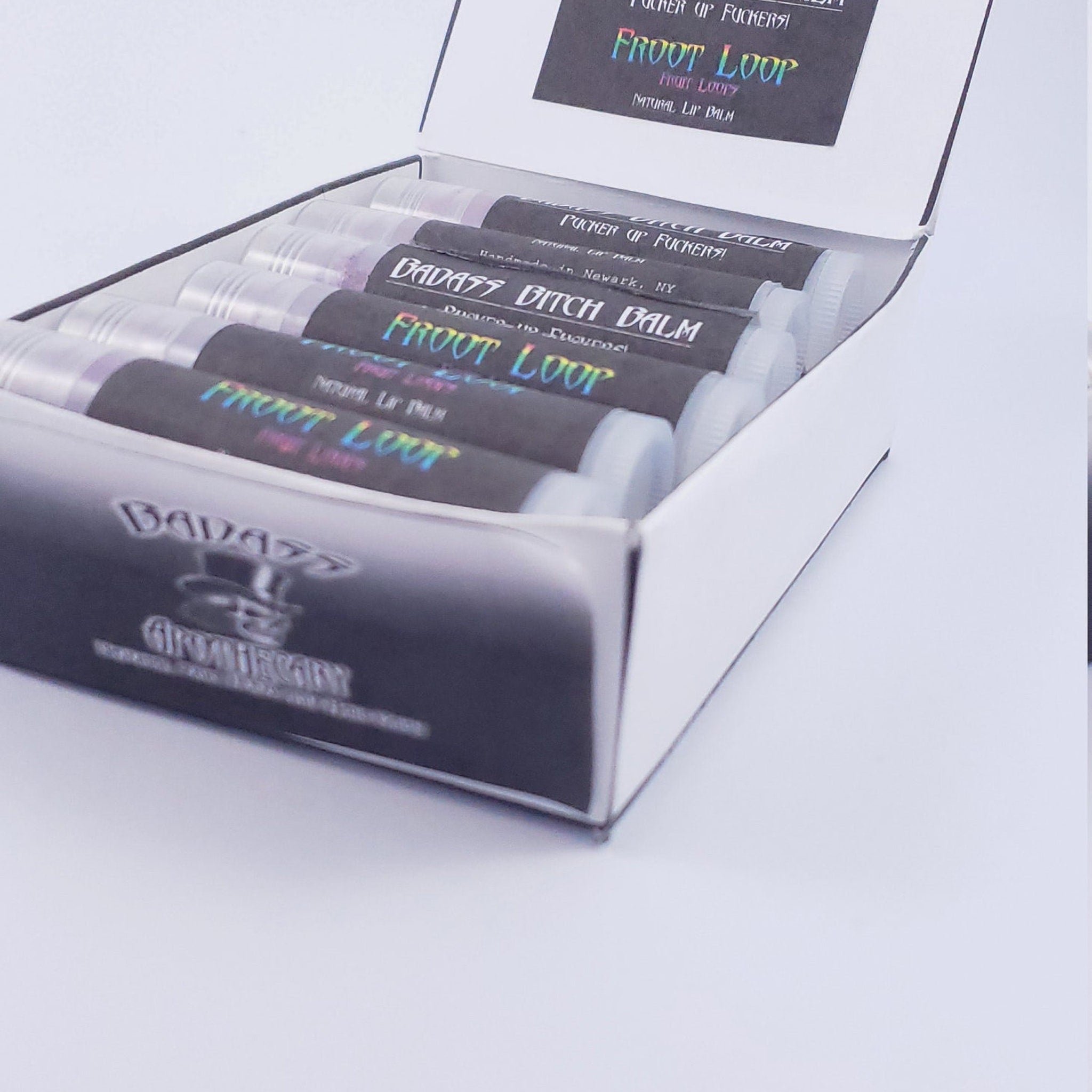 Lip balm tubes with black labels, holographic text, and white caps in a white box